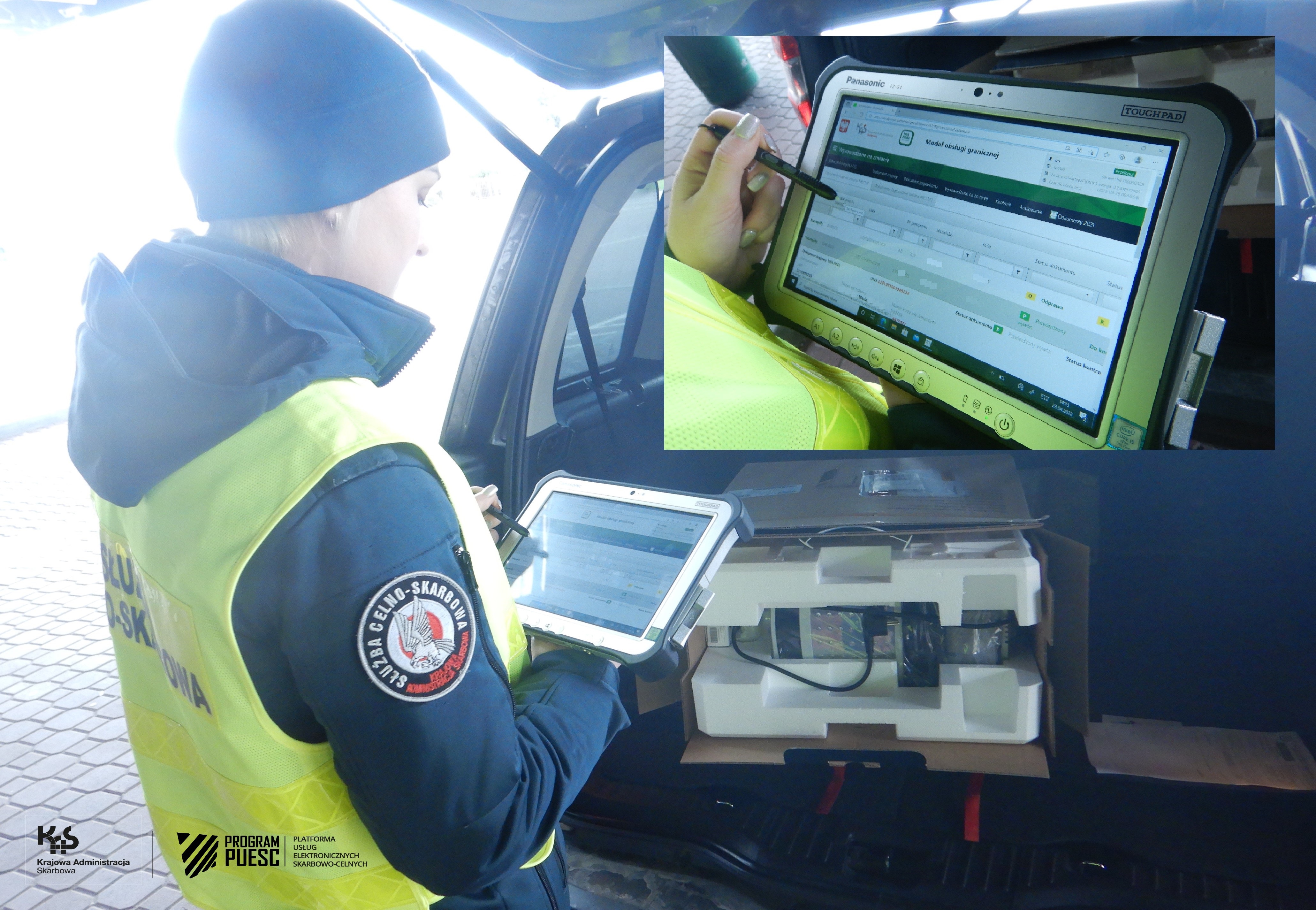 Funkcjonariuszka obsługująca tablet na przejściu granicznym, w tle widać samochód z otwartym bagażnikiem i otwartym kartonem w środku.